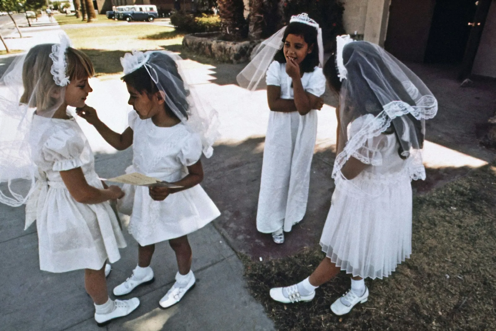Girls in white First Communion dresses and veils standing together outdoors, 1972